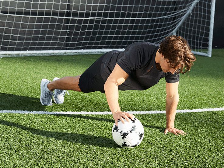 Fußballspieler macht Liegestütze mit Ball vor dem Tor, um Angst im Sport zu überwinden und sich mental auf Wettkampfangst vorzubereiten.