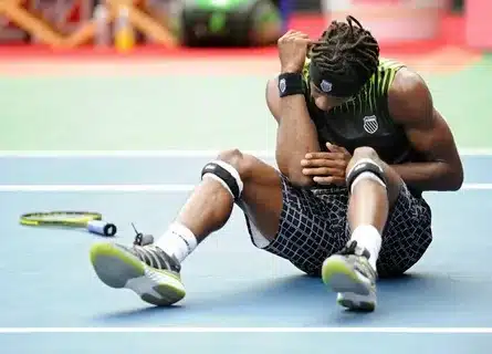 Tennisspieler sitzt verletzt auf dem Platz und hält sich den Arm – Symbol für Mentaltraining nach Sportverletzung, um Rückkehr, Vertrauen und mentale Stärke zu unterstützen.