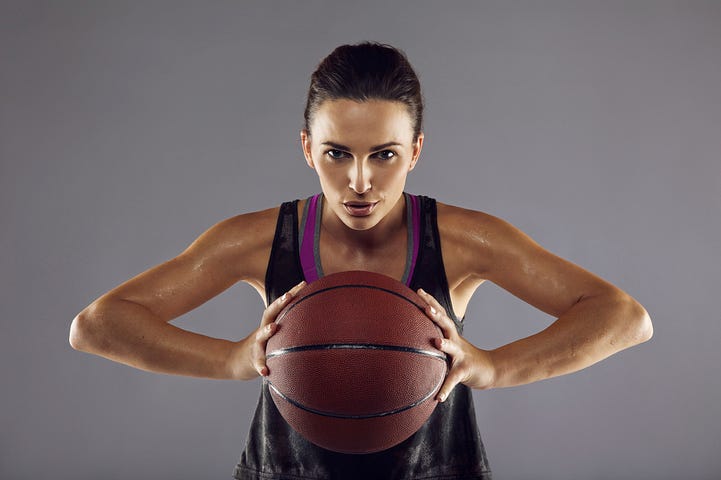 Fokussierte Basketballspielerin mit Ball vor neutralem Hintergrund, die mentale Stärke und Leistungsfähigkeit durch Sportpsychologie Berlin verkörpert.