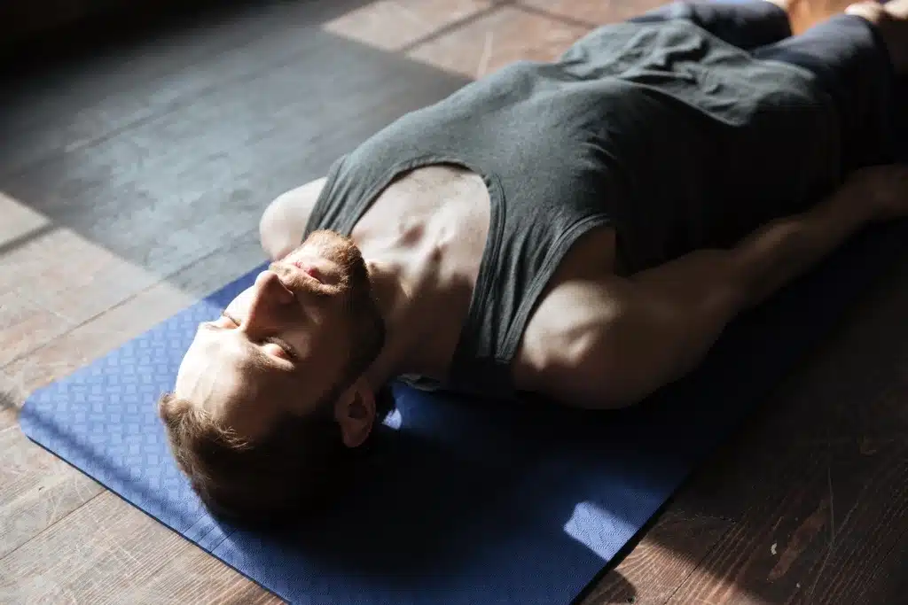 Athlet liegt entspannt auf einer Matte und konzentriert sich auf seinen Körper – Symbol für Neurofeedback Training zur Verbesserung von Ruhe, Fokus und Regeneration.